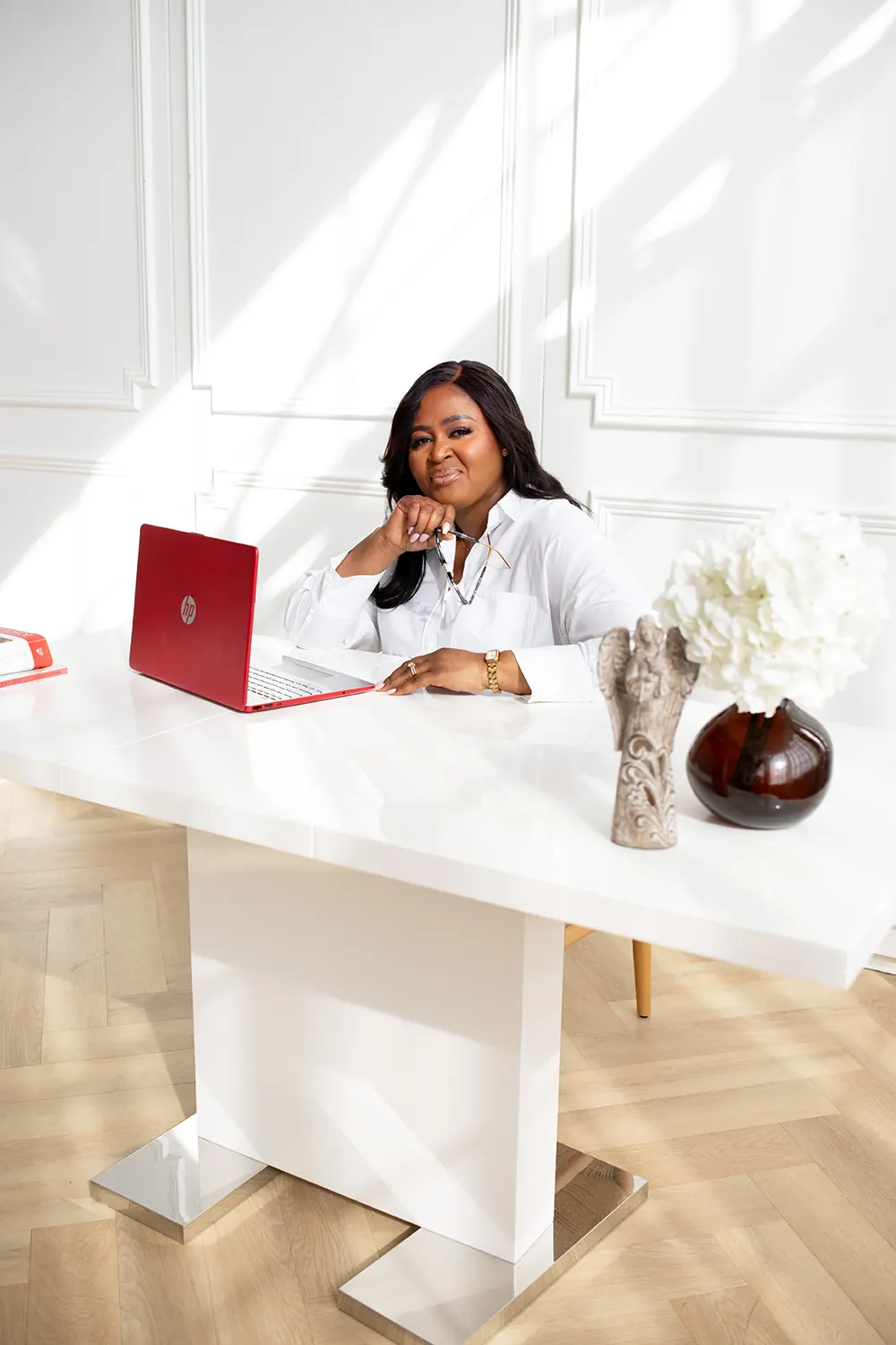 Therapist seated at her desk with a laptop and flowers