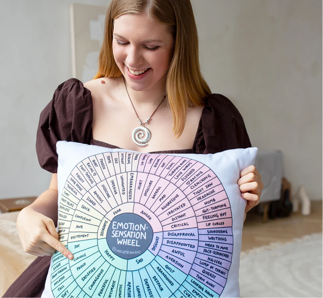 A smiling therapist holding an emotion wheel cushion